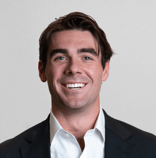 Headshot of a smiling man in a dark jacket